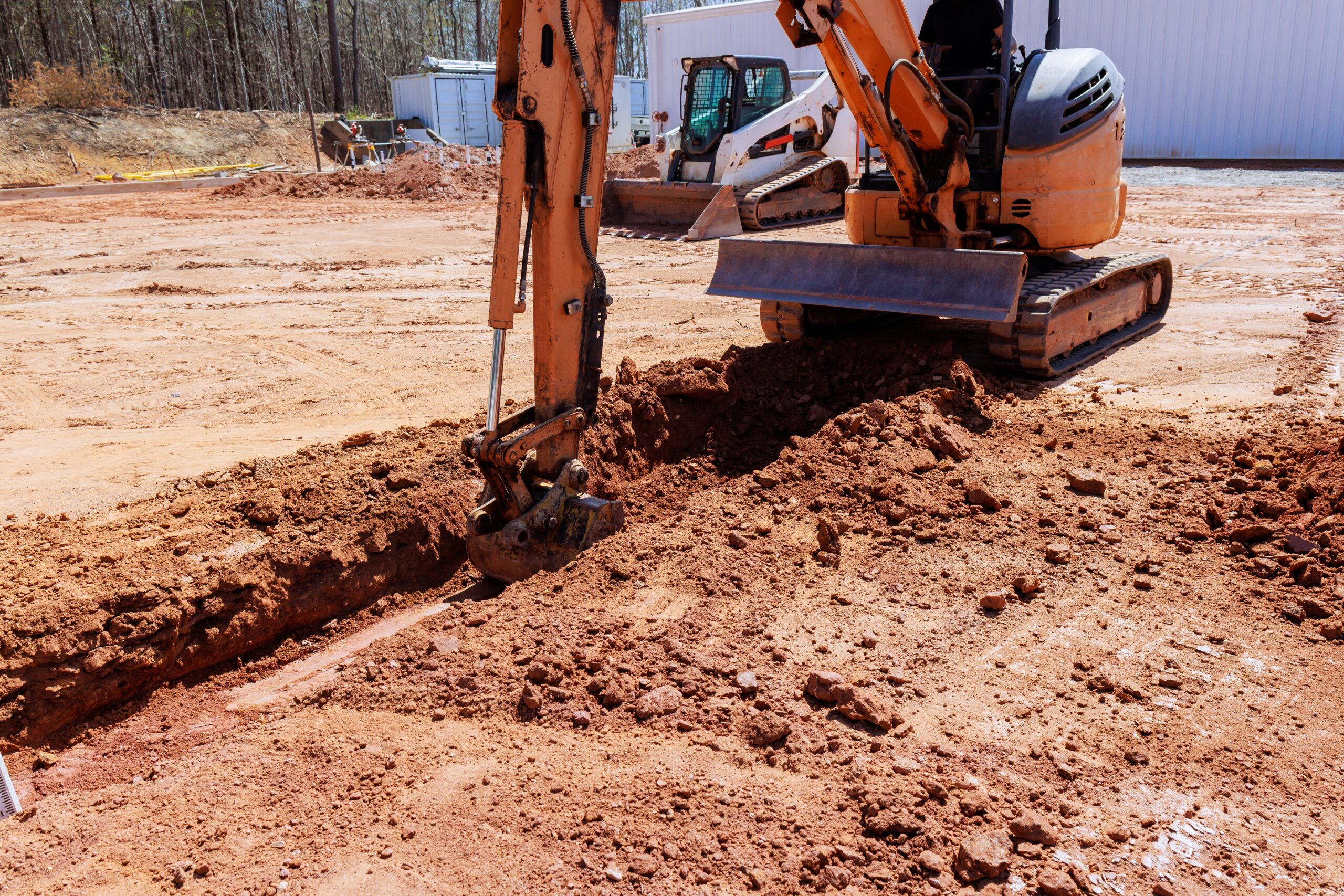 Yellow mini trencher digging into red clay soil for utility installation in Northeast Texas